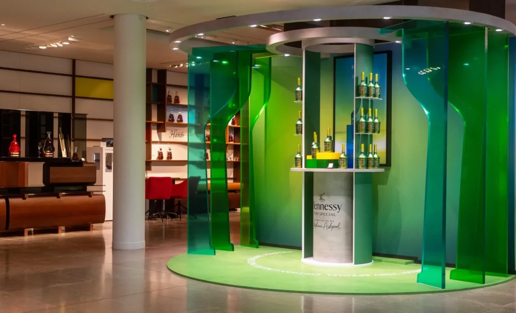 Boutique de la marque hennessy avec en premier plan des plexiglass en dégradé de verts et une étagère avec des bouteilles de VSOP édition spéciale crées par le créateur Stéphane Ashpool