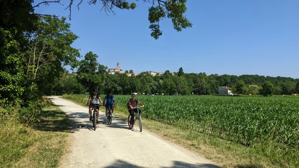 La Flow Vélo itinéraire dédié aux mobilités douces le long de la Charente à St-Simeux, cyclistes au pied du village avec l'église en arrière plan