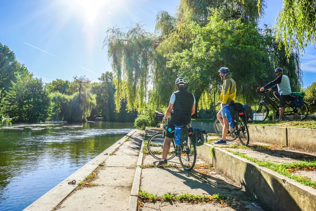 La Flow Vélo itinéraire dédié aux mobilités douces le long de la Charente à Cognac en passant par Jarnac, cyclistes faisant une pause en bord de Charente à Jarnac sous les saules pleureurs