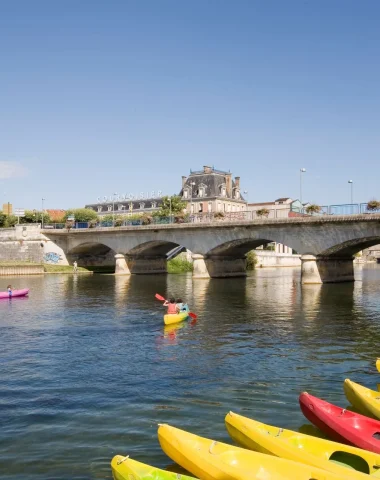 The charente river at jarnac, in the foreground canoes from the jarnac canoe kayak club, in the background the bridge linking gondeville to jarnac, in the background the courvoisier cognac house