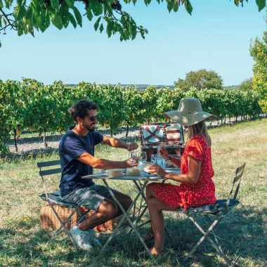 Un couple savoure un pique-nique en amoureux dans le vignoble de cognac à l'ombre d'un cerisier.