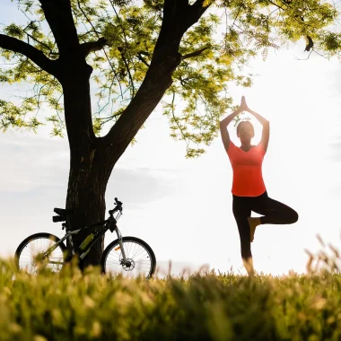Femme avec son vélo faisant une pause yoga en pleine nature