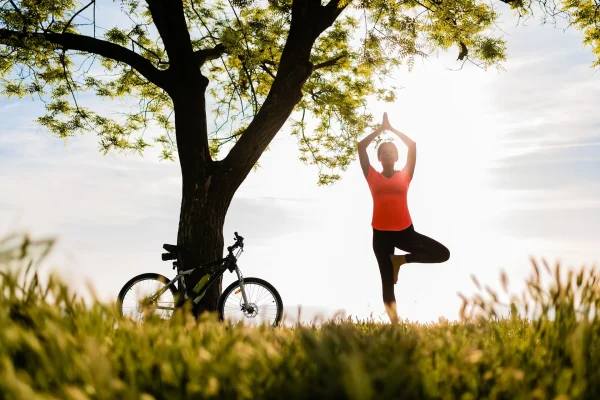 Femme avec son vélo faisant une pause yoga en pleine nature