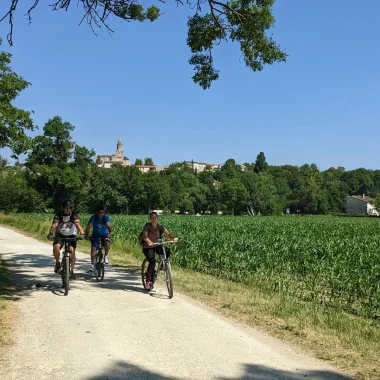 The Flow Vélo cycle route along the Charente in St-Simeux, cyclists at the foot of the village with the church in the background