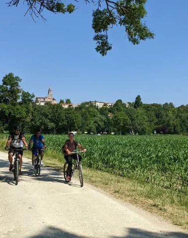 The Flow Vélo cycle route along the Charente in St-Simeux, cyclists at the foot of the village with the church in the background