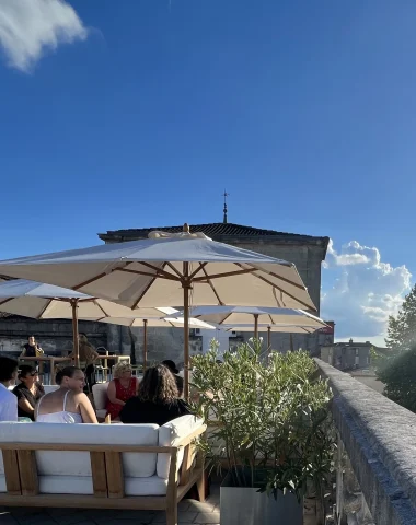 A group of friends enjoying a drink at the end of the day on the rooftop of Le Lys, the Château de Cognac bar, with a view of the Charente river.