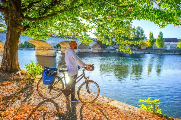 La Flow Vélo itinéraire dédié aux mobilités douces le long de la Charente à Cognac, cycliste admirant la vue sur le Pont Saint Jacques et les quais de Cognac