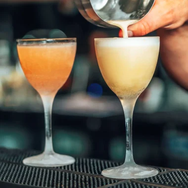 Barman qui vers la préparation d'un cocktail dans un verre